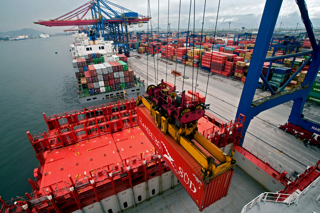 Guindaste realizando carregamento de container em navio em operação portuária.