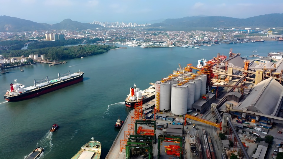 Navio cargueiro em terminal portuário com movimentação de contêineres e automação operacional.